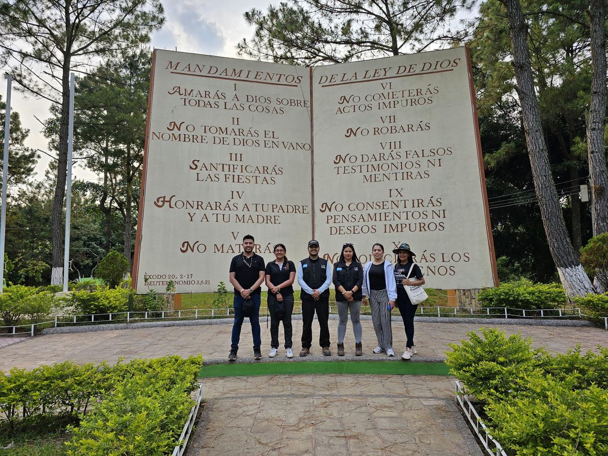 Grupo frente a un gran monumento de piedra con los Mandamientos en un parque