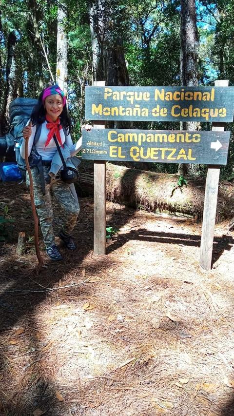 Excursionista junto al rótulo «Parque Nacional Montaña de Celaque, Campamento El Quetzal»